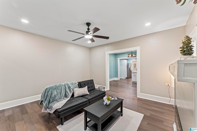 living room featuring dark wood-type flooring and ceiling fan