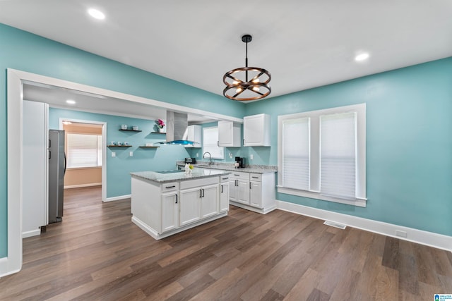 kitchen featuring hanging light fixtures, white cabinetry, wall chimney exhaust hood, stainless steel refrigerator, and dark hardwood / wood-style floors