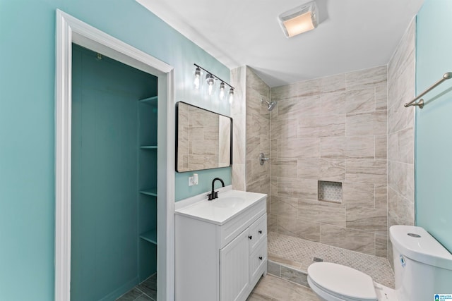 bathroom featuring vanity, toilet, tiled shower, and tile patterned flooring