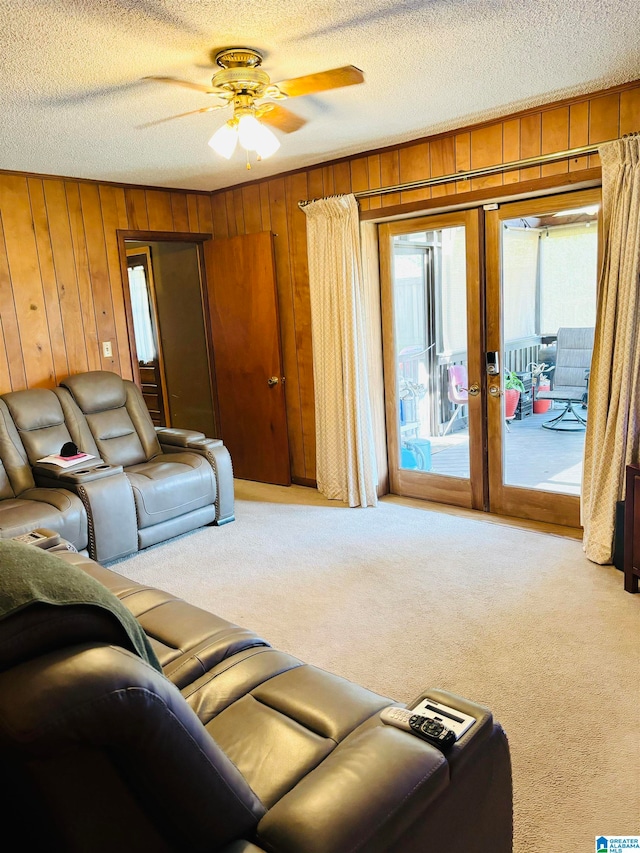 carpeted living room with wooden walls, a textured ceiling, and ceiling fan