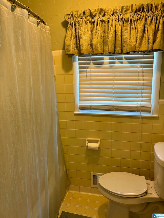 bathroom with walk in shower, plenty of natural light, toilet, and tile patterned flooring