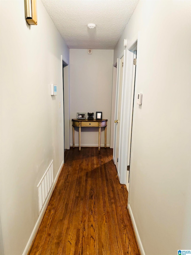 hall featuring a textured ceiling and dark hardwood / wood-style flooring