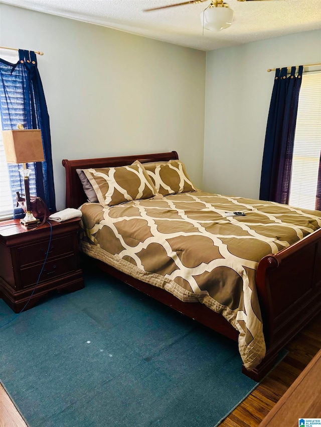 bedroom featuring ceiling fan, wood-type flooring, and a textured ceiling