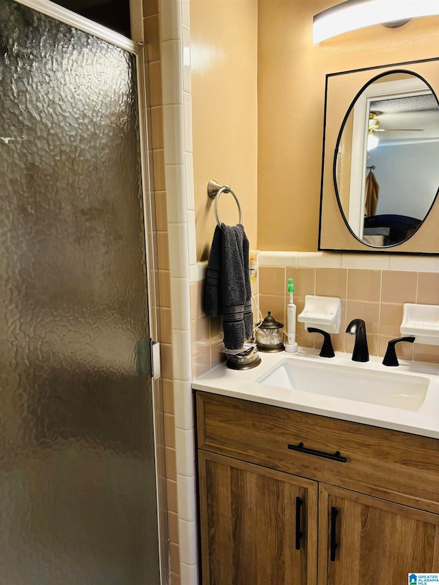 bathroom featuring a shower with door, vanity, and tasteful backsplash