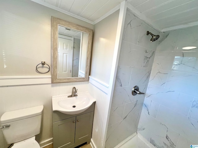 bathroom featuring vanity, ornamental molding, toilet, and tiled shower