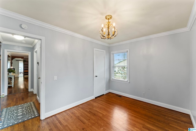 spare room featuring wood-type flooring, an inviting chandelier, and crown molding