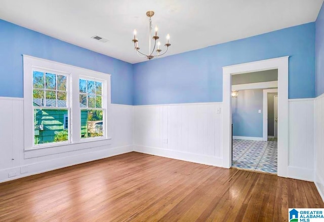 empty room with hardwood / wood-style flooring and a notable chandelier