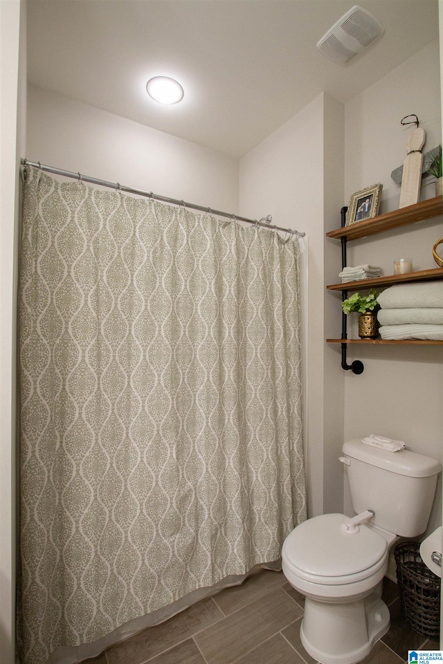 bathroom with wood-type flooring, toilet, and walk in shower