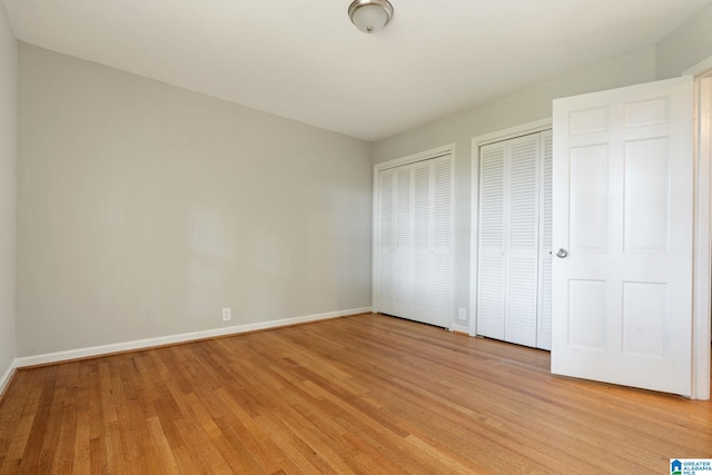 unfurnished bedroom with multiple closets and light hardwood / wood-style flooring