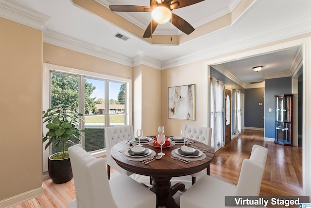 dining area with ceiling fan, crown molding, a tray ceiling, and hardwood / wood-style floors