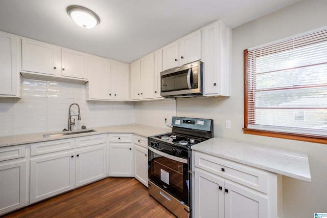 kitchen with light stone countertops, sink, white cabinetry, stainless steel appliances, and dark hardwood / wood-style floors