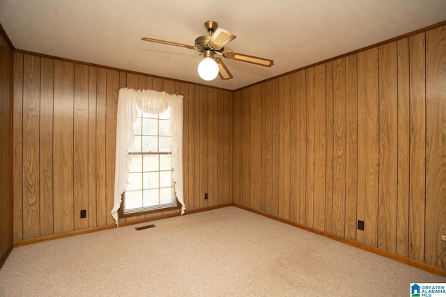 carpeted spare room with ceiling fan and wood walls