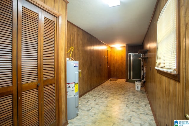 basement featuring electric water heater and wooden walls