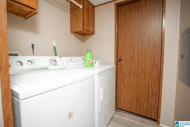 laundry room with electric panel, light wood-type flooring, separate washer and dryer, and cabinets