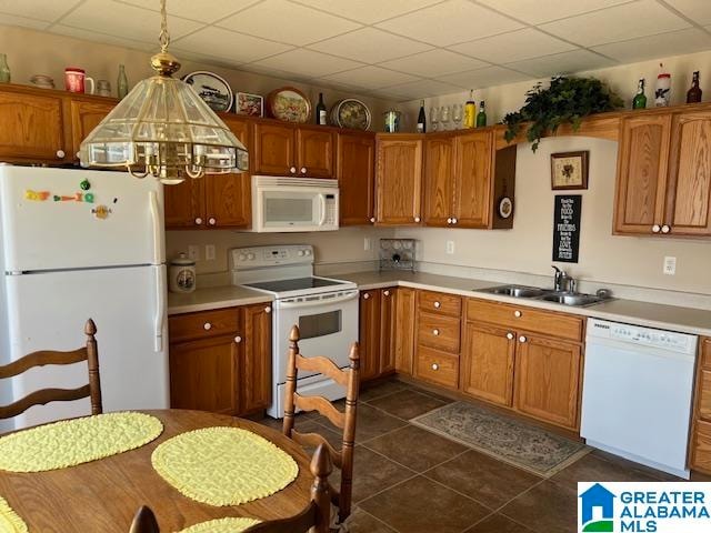 kitchen featuring dark tile patterned flooring, hanging light fixtures, sink, a paneled ceiling, and white appliances