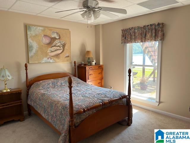 bedroom featuring a drop ceiling, carpet, and ceiling fan