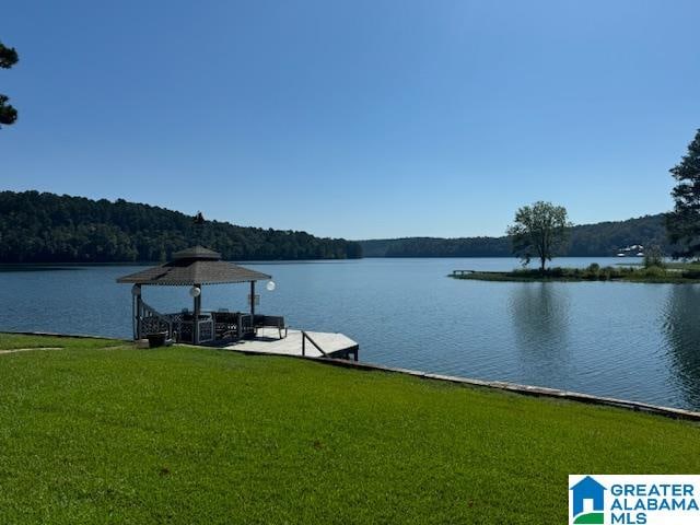 view of dock with a yard and a water view