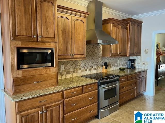 kitchen with stone countertops, wall chimney range hood, stainless steel appliances, and light tile patterned floors