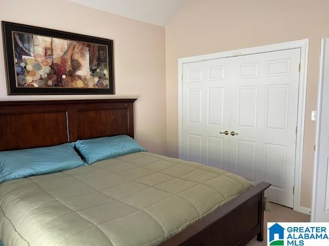 carpeted bedroom with a closet and lofted ceiling