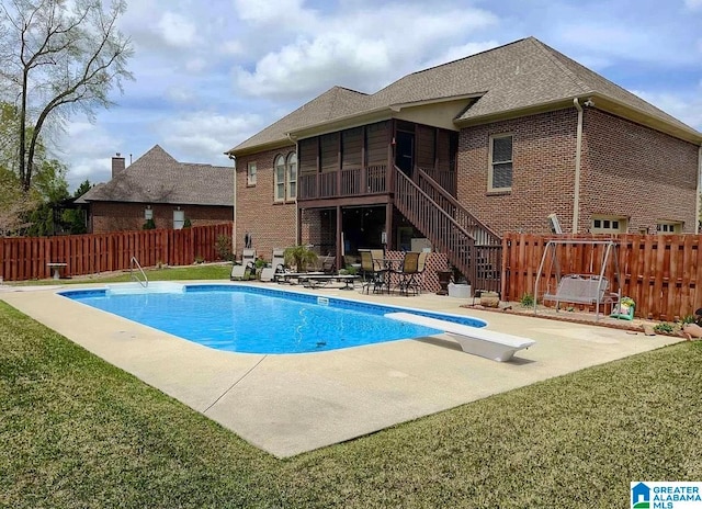 view of pool featuring a patio area, a lawn, a diving board, and a sunroom