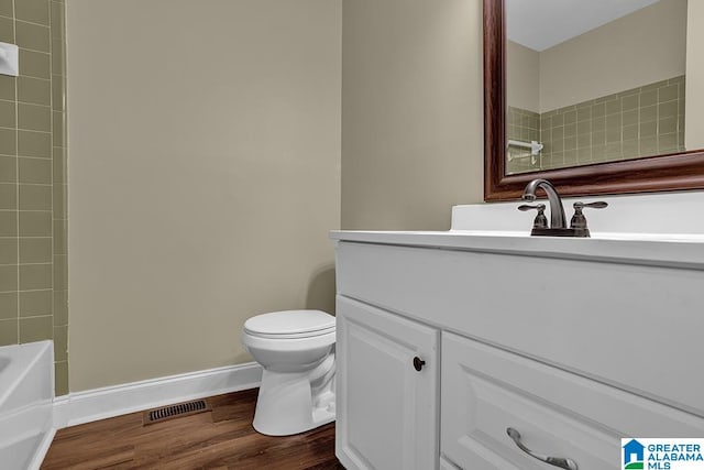 full bathroom with toilet, hardwood / wood-style floors, tiled shower / bath combo, and vanity