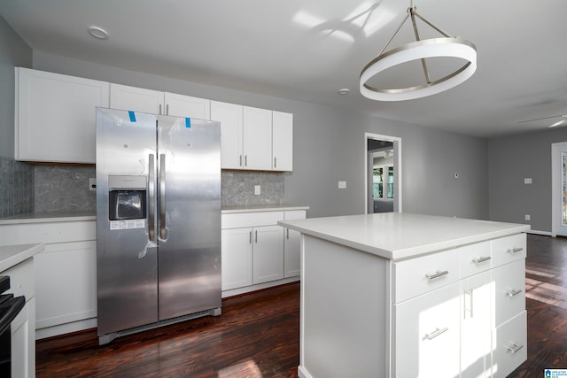 kitchen featuring dark wood-type flooring, stainless steel fridge, pendant lighting, decorative backsplash, and white cabinets