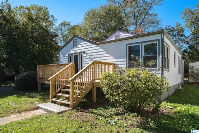 back of property featuring a lawn and a wooden deck