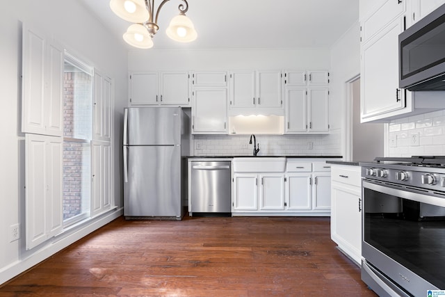 kitchen featuring appliances with stainless steel finishes, white cabinetry, tasteful backsplash, and dark hardwood / wood-style floors