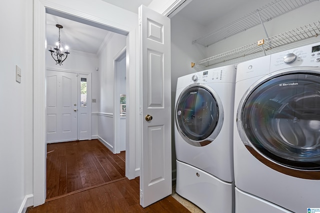 laundry room with an inviting chandelier, ornamental molding, separate washer and dryer, and dark hardwood / wood-style flooring