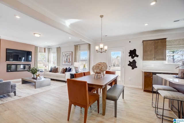 dining room featuring light hardwood / wood-style floors, crown molding, and plenty of natural light