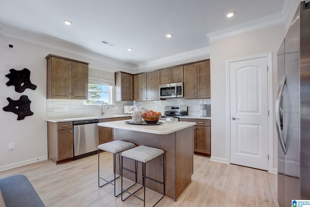 kitchen featuring light hardwood / wood-style flooring, a center island, stainless steel appliances, and crown molding