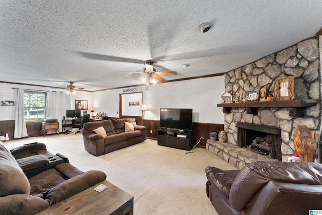 carpeted living room with ceiling fan, a textured ceiling, wood walls, a fireplace, and crown molding