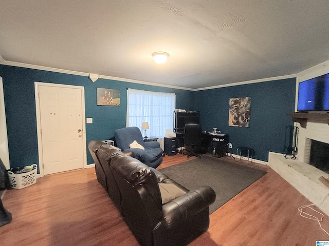 living room with ornamental molding, wood-type flooring, and a brick fireplace