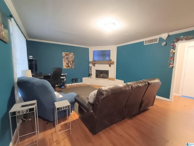 living room featuring crown molding, wood-type flooring, and a brick fireplace