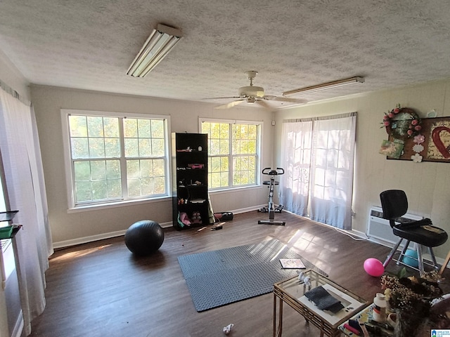 exercise room featuring ceiling fan, hardwood / wood-style flooring, and a textured ceiling