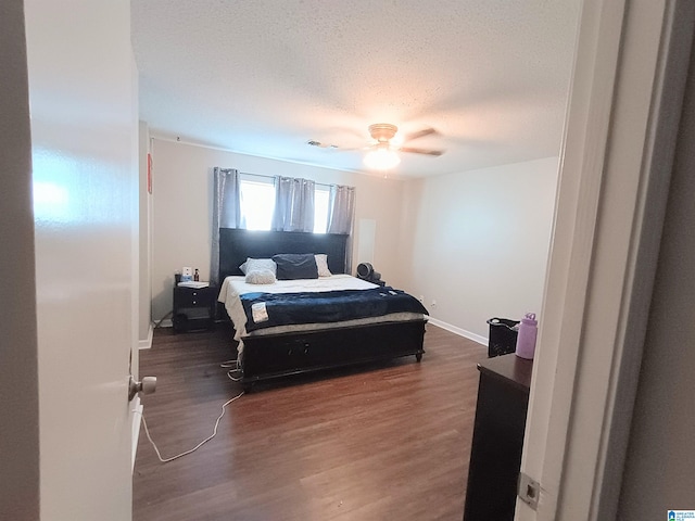 bedroom with dark wood-type flooring, ceiling fan, and a textured ceiling