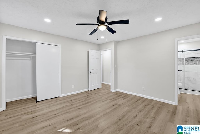 unfurnished bedroom featuring light hardwood / wood-style floors, a closet, ensuite bath, and ceiling fan