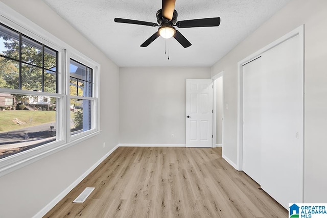 interior space with a textured ceiling, light wood-type flooring, and ceiling fan