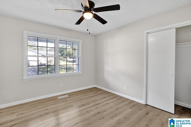 unfurnished bedroom featuring ceiling fan, a textured ceiling, and light wood-type flooring