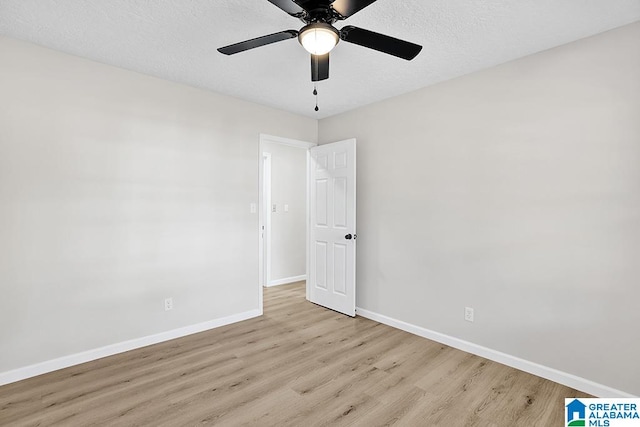 spare room featuring a textured ceiling, light wood-type flooring, and ceiling fan