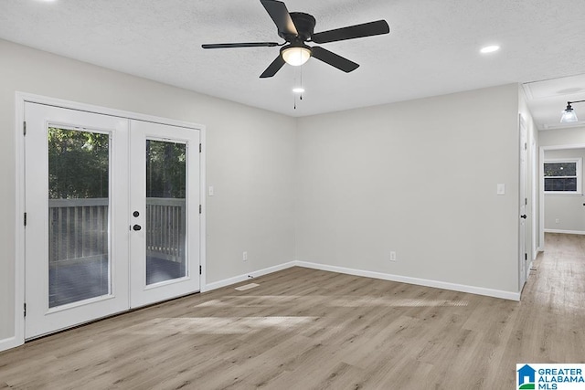 empty room with french doors, a textured ceiling, light wood-type flooring, and ceiling fan