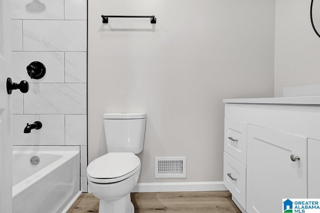 full bathroom featuring tiled shower / bath, vanity, hardwood / wood-style floors, and toilet