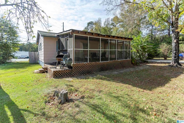 back of house featuring a sunroom and a lawn