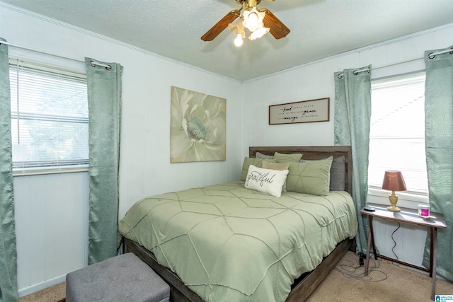 bedroom with a textured ceiling, light colored carpet, multiple windows, and ceiling fan