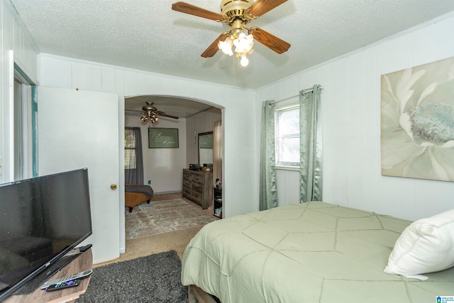 carpeted bedroom featuring ornamental molding, a textured ceiling, and ceiling fan