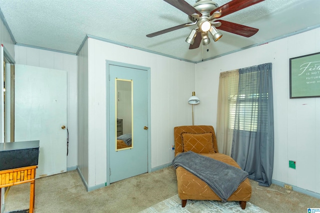 living area featuring crown molding, a textured ceiling, light carpet, wooden walls, and ceiling fan