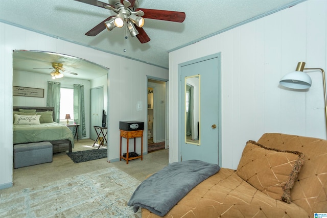 bedroom with ornamental molding, ceiling fan, a textured ceiling, and light colored carpet