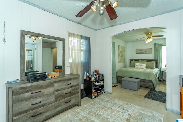 carpeted bedroom featuring ceiling fan, a textured ceiling, and wooden walls