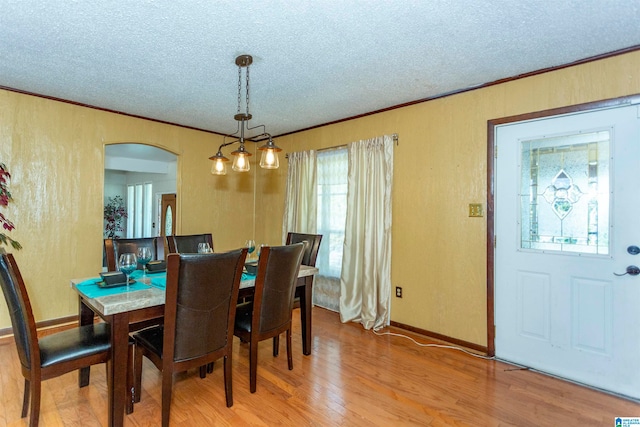 dining space with light hardwood / wood-style floors, a textured ceiling, and crown molding