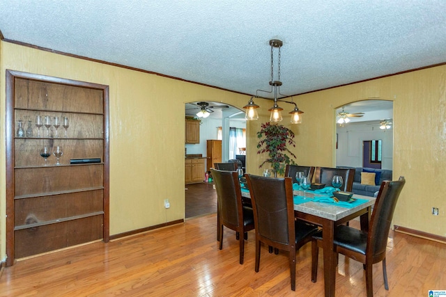 dining area with a textured ceiling, light wood-type flooring, and ornamental molding